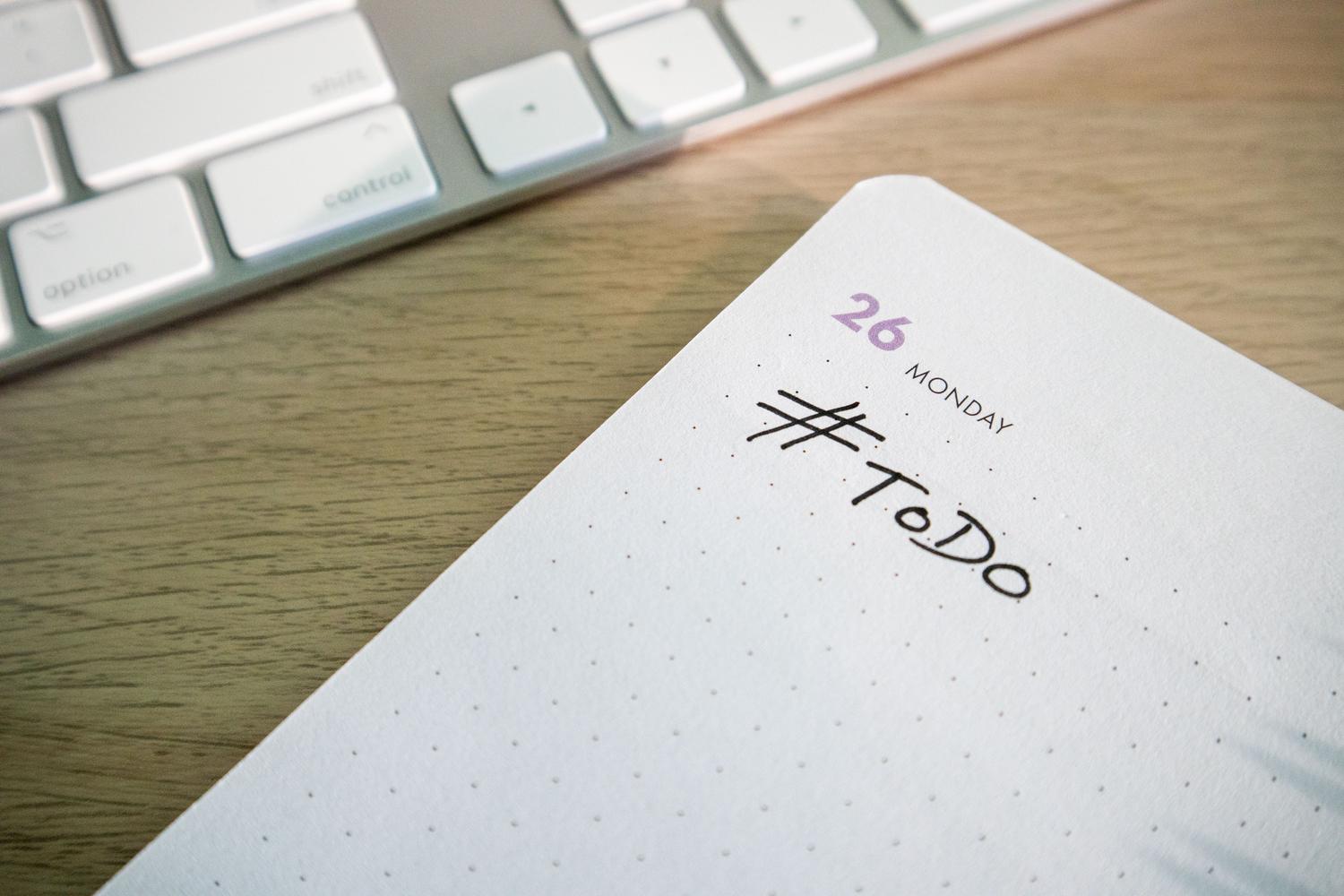 Primer plano de una lista de tareas pendientes junto a un teclado, representando la gestión de tareas y bases de datos.