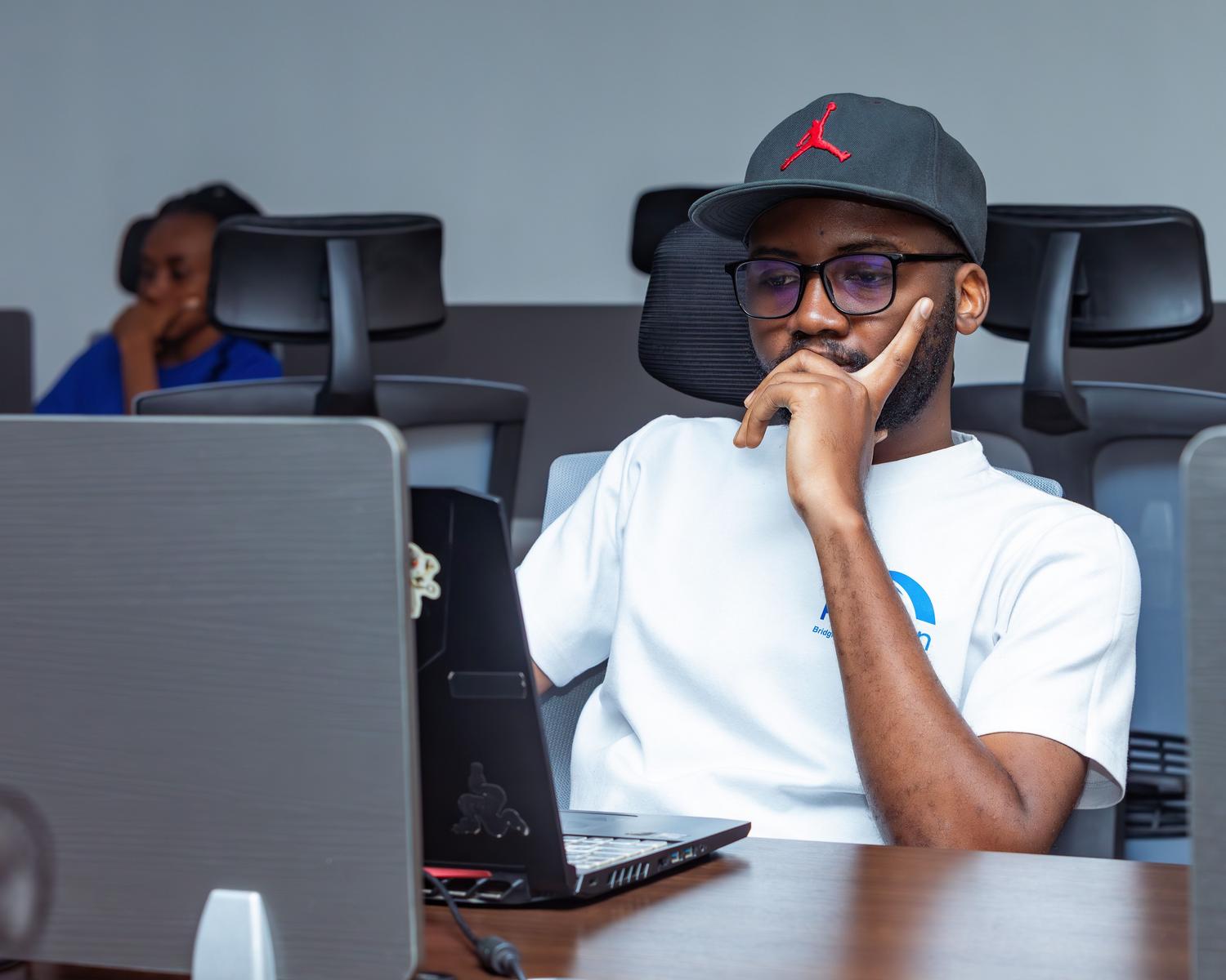 Joven profesional trabajando concentrado con su ordenador portátil en una oficina contemporánea, ilustrando el perfil de power user o freelancer.