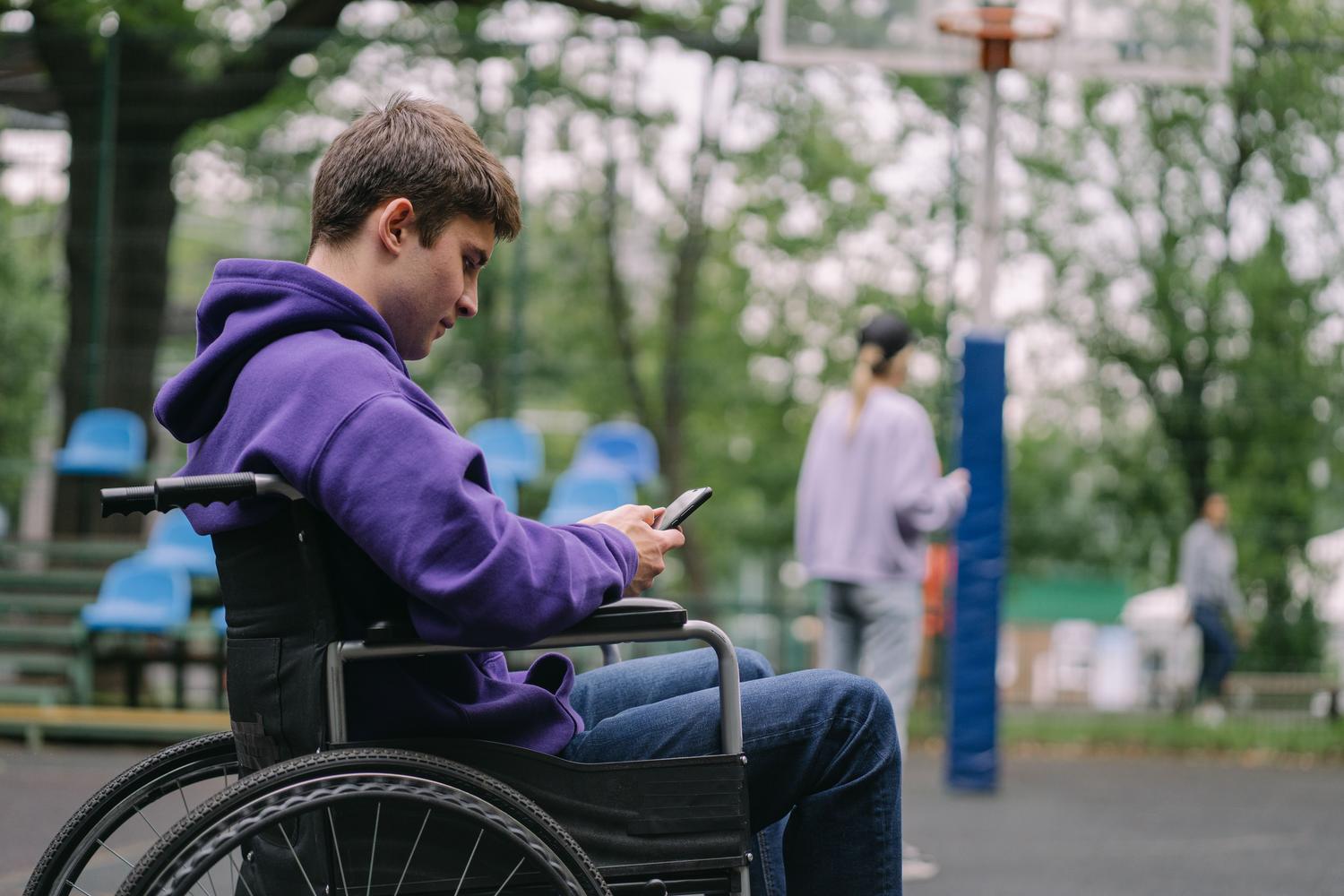 Joven con movilidad reducida usando un dispositivo Android en un parque público.