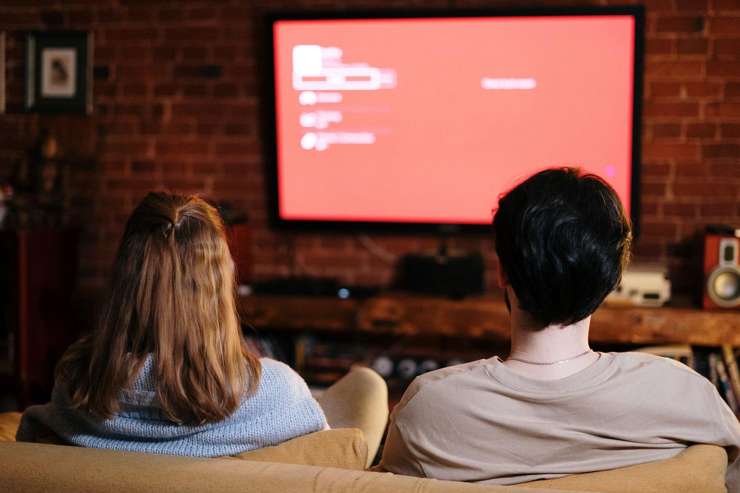 Pareja disfrutando de contenido en su Smart TV en un salón acogedor, representando el consumo de ocio en casa.