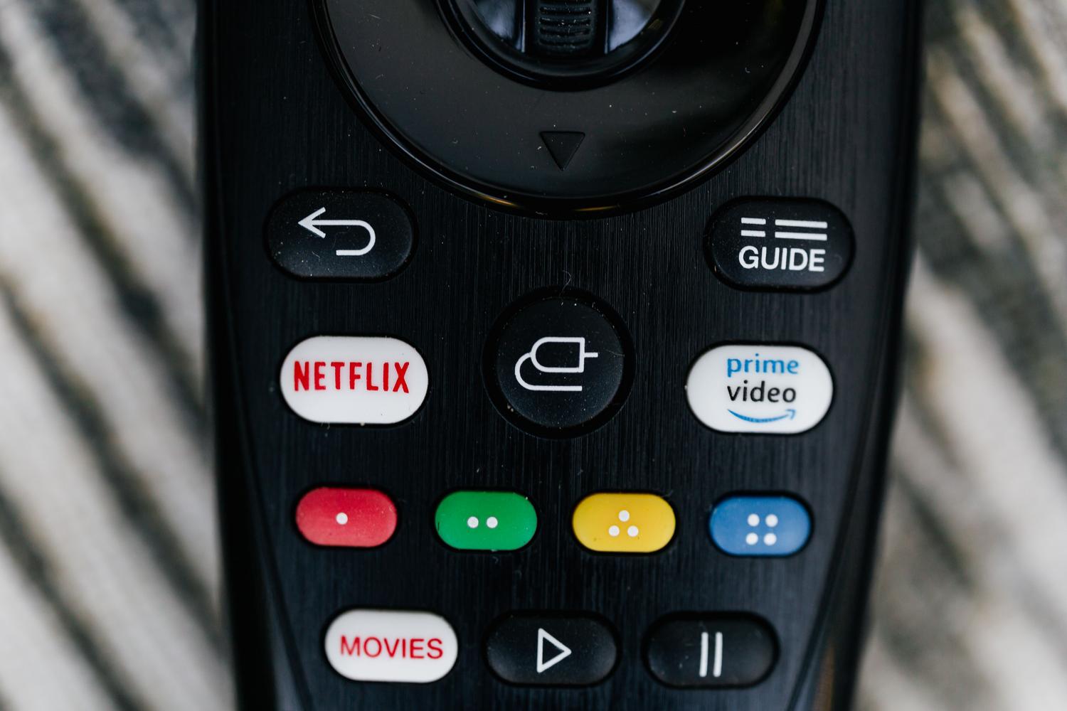 Primer plano detallado de un mando a distancia de televisión con botones de servicios de streaming, ideal para ilustrar el acceso a los ajustes.