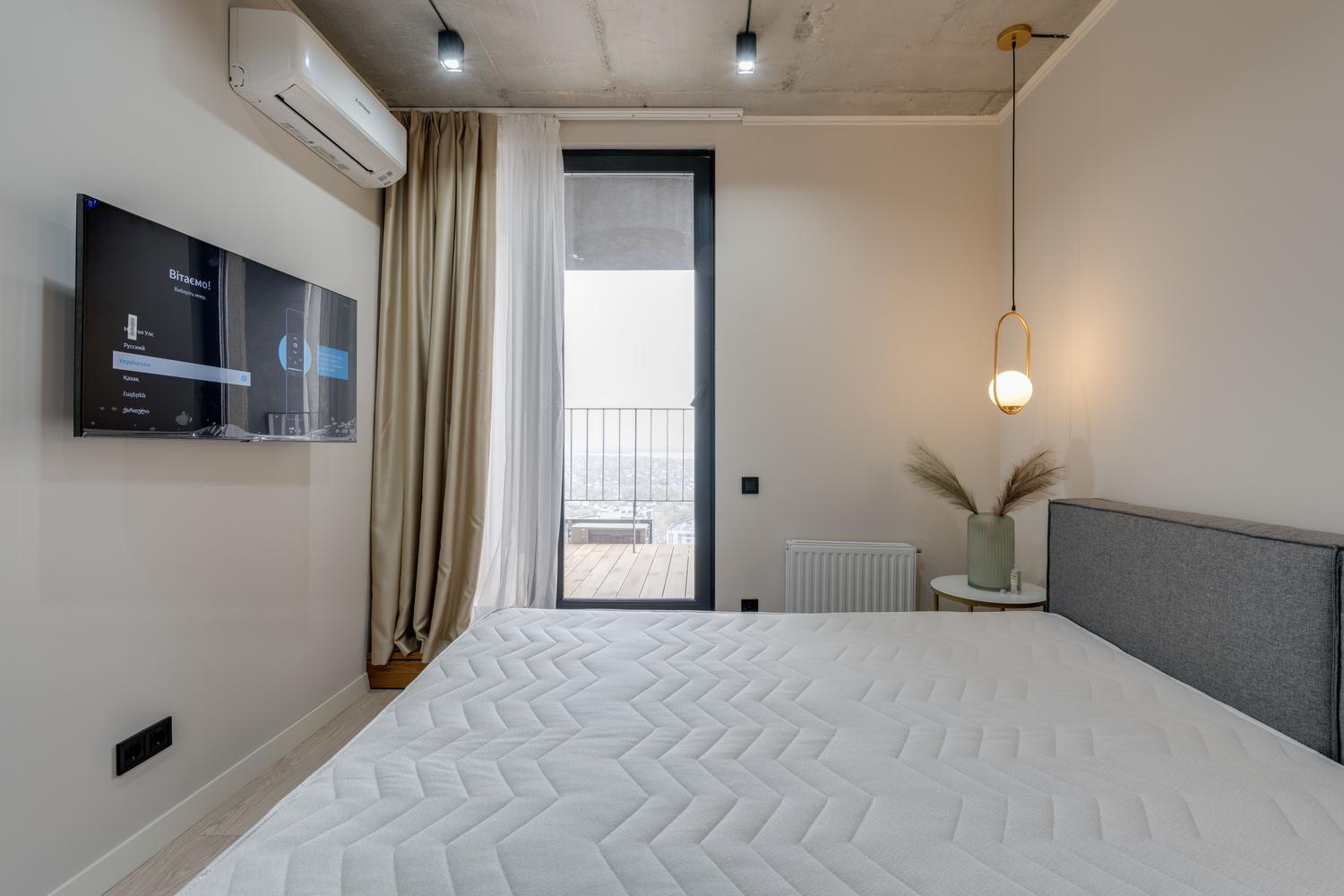 Dormitorio moderno con televisor montado en la pared, ideal para configurar el modo nocturno y Eye Comfort.