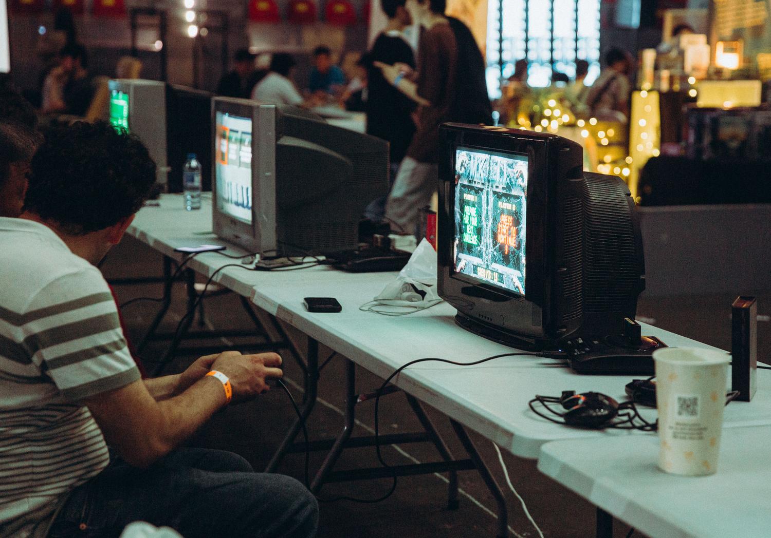 Personas jugando videojuegos clásicos en televisores de tubo CRT en un ambiente nostálgico.