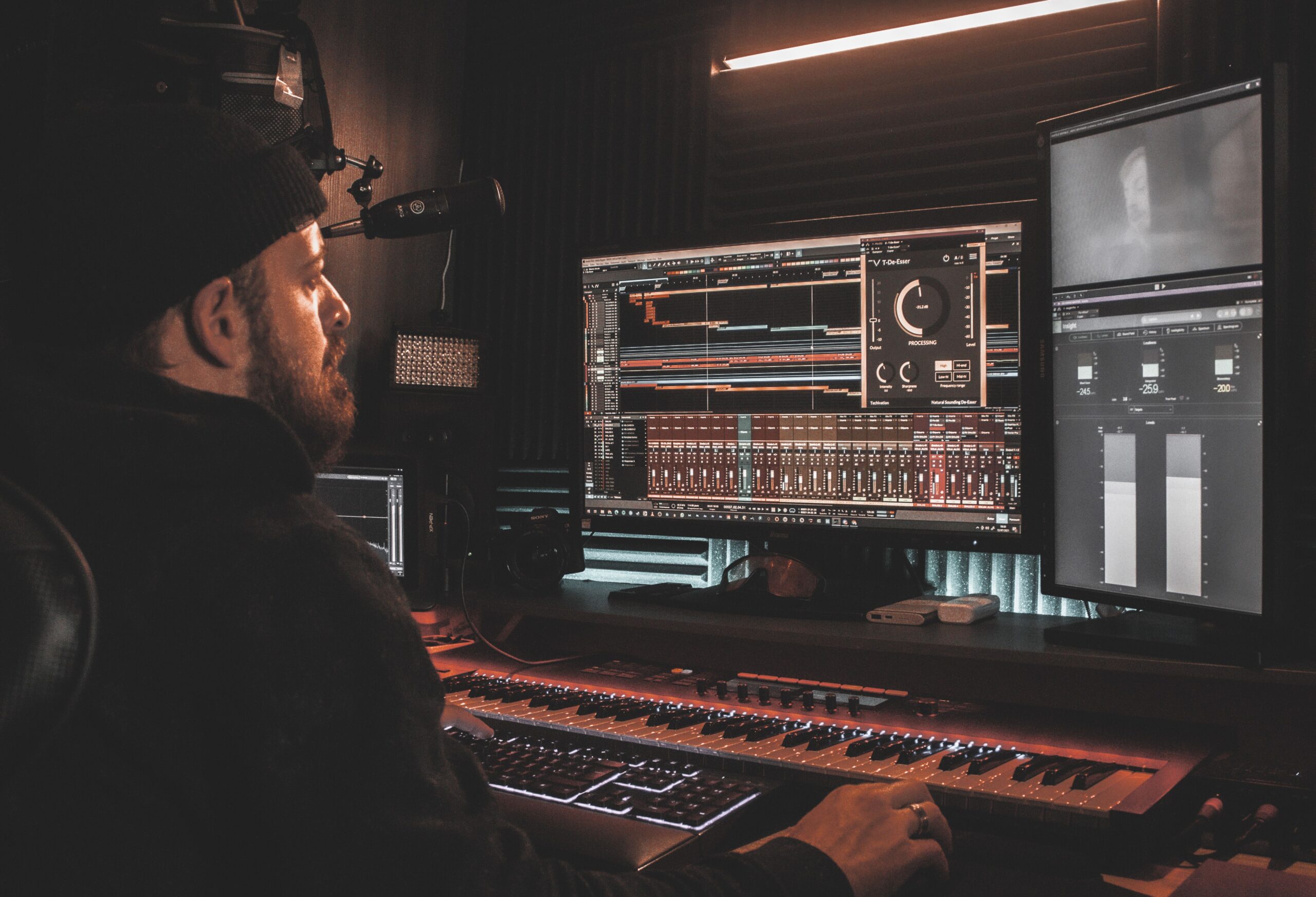 Ingeniero de sonido profesional concentrado trabajando en una estación de trabajo digital (DAW) en un estudio equipado.