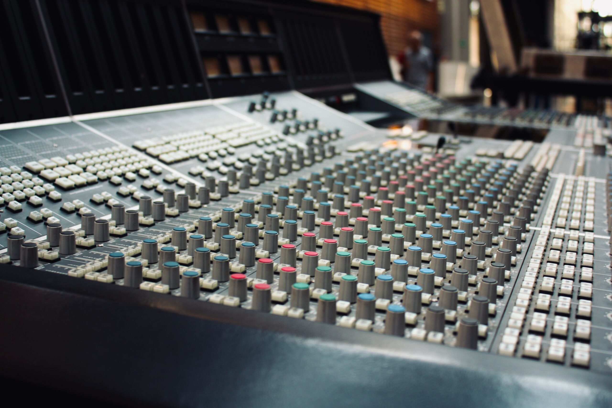 Detalle macro de una consola de mezclas de audio profesional, resaltando la calidad del hardware utilizado en entornos de producción musical.