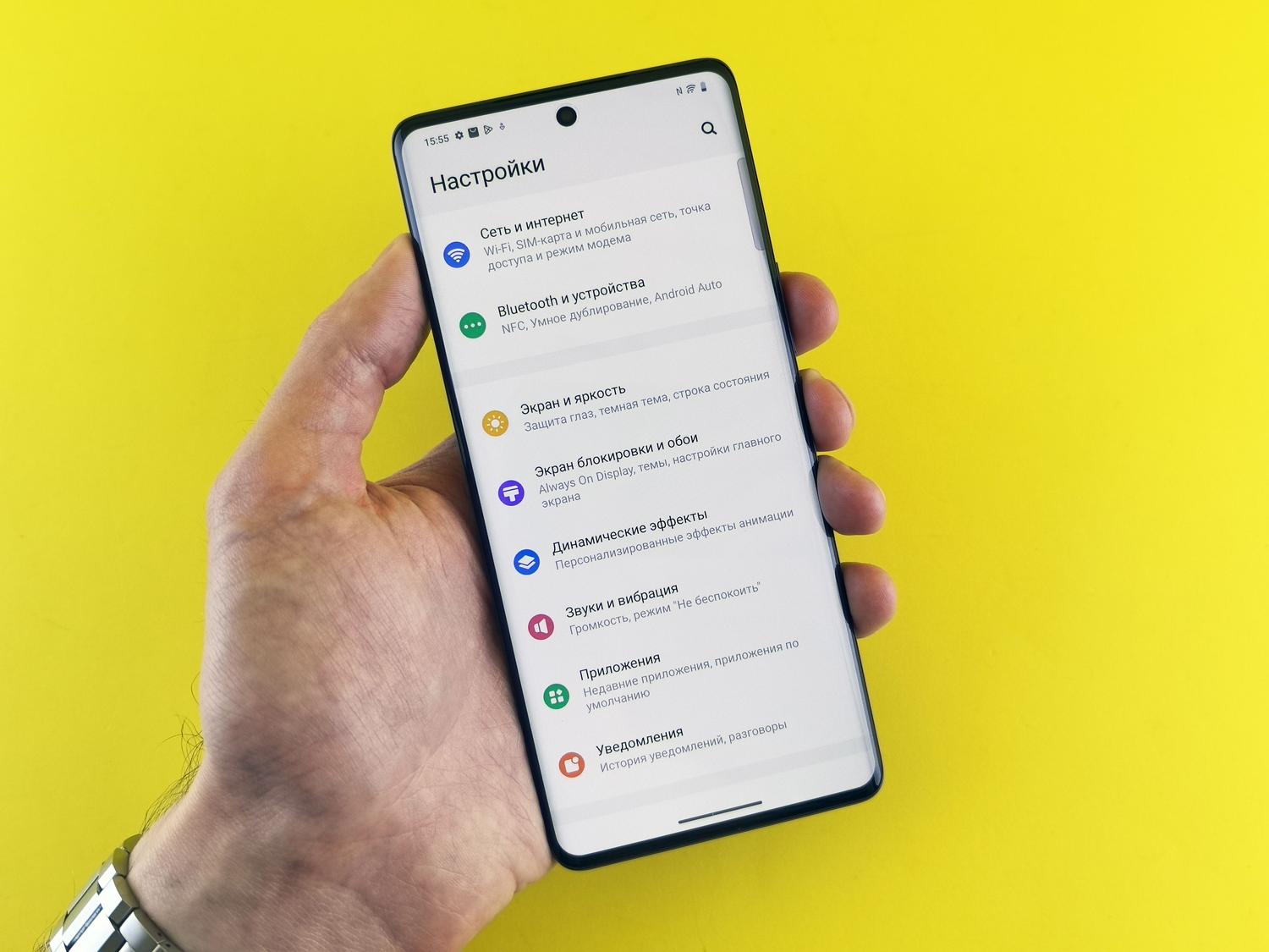 Persona sosteniendo un smartphone con el menú de ajustes de Android abierto para gestionar los permisos del sistema.
