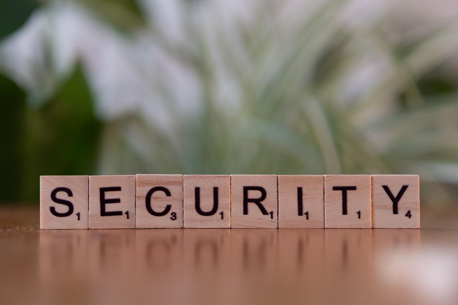 Letras de madera formando la palabra SECURITY, representando el blindaje del dispositivo contra malware y botnets.