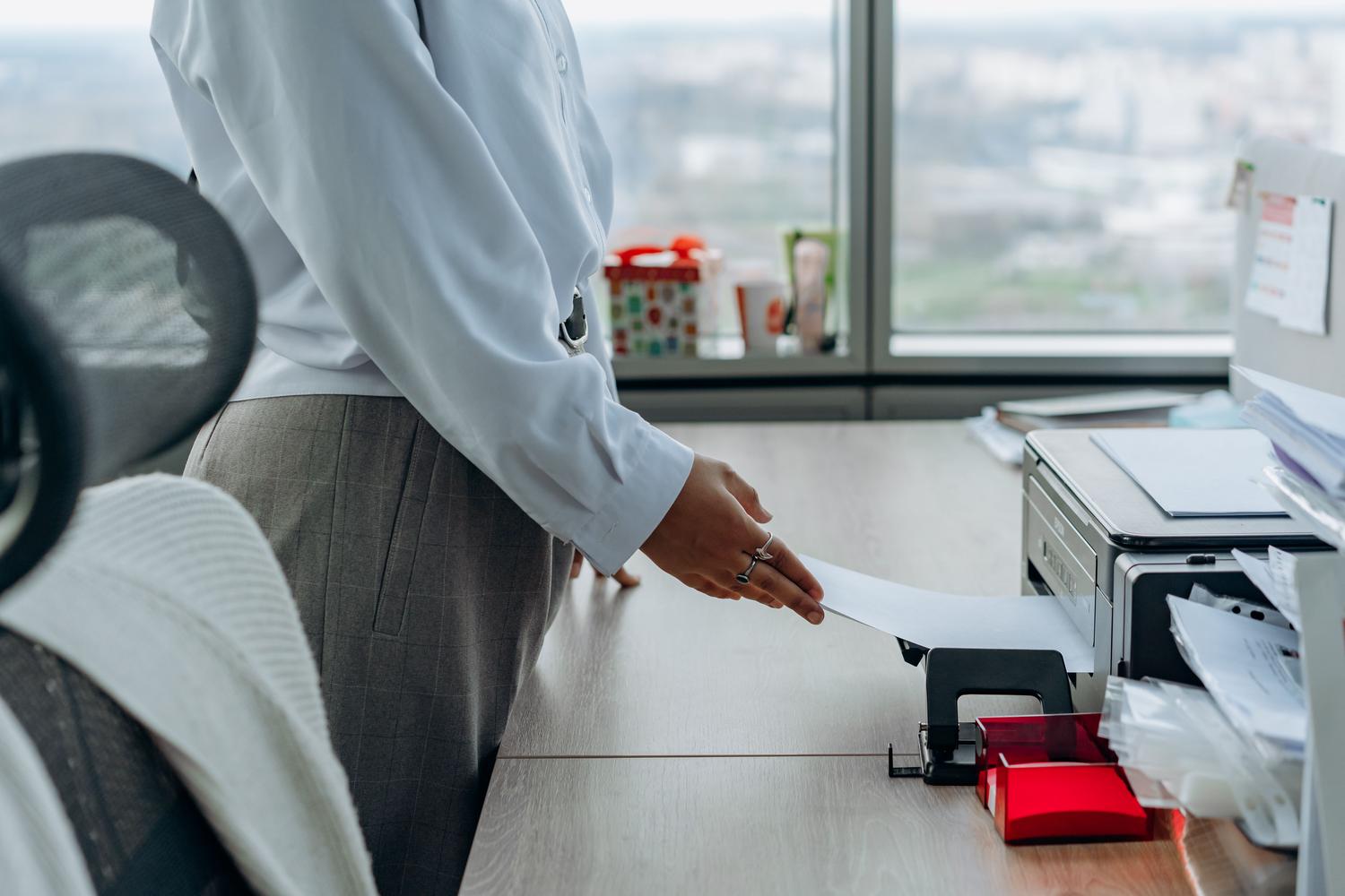 Profesional de oficina recogiendo documentos impresos de una impresora de red