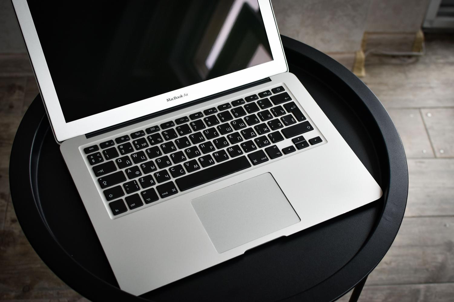MacBook Pro abierto sobre una mesa negra minimalista, ideal como imagen principal para un artículo de ajustes de red en macOS.