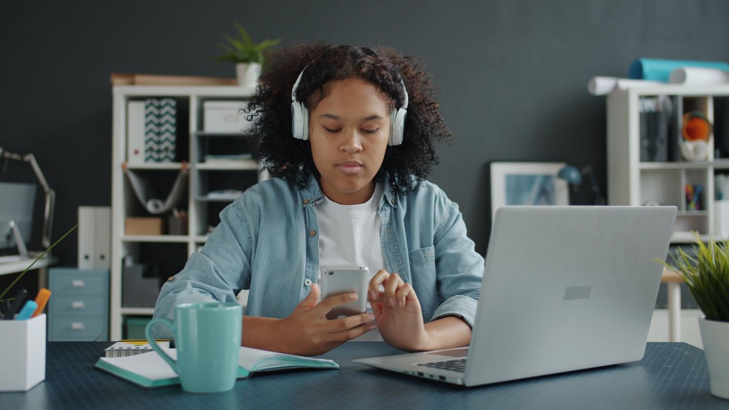 Persona utilizando un smartphone y un portátil simultáneamente para comprobar la conectividad de red en varios dispositivos.