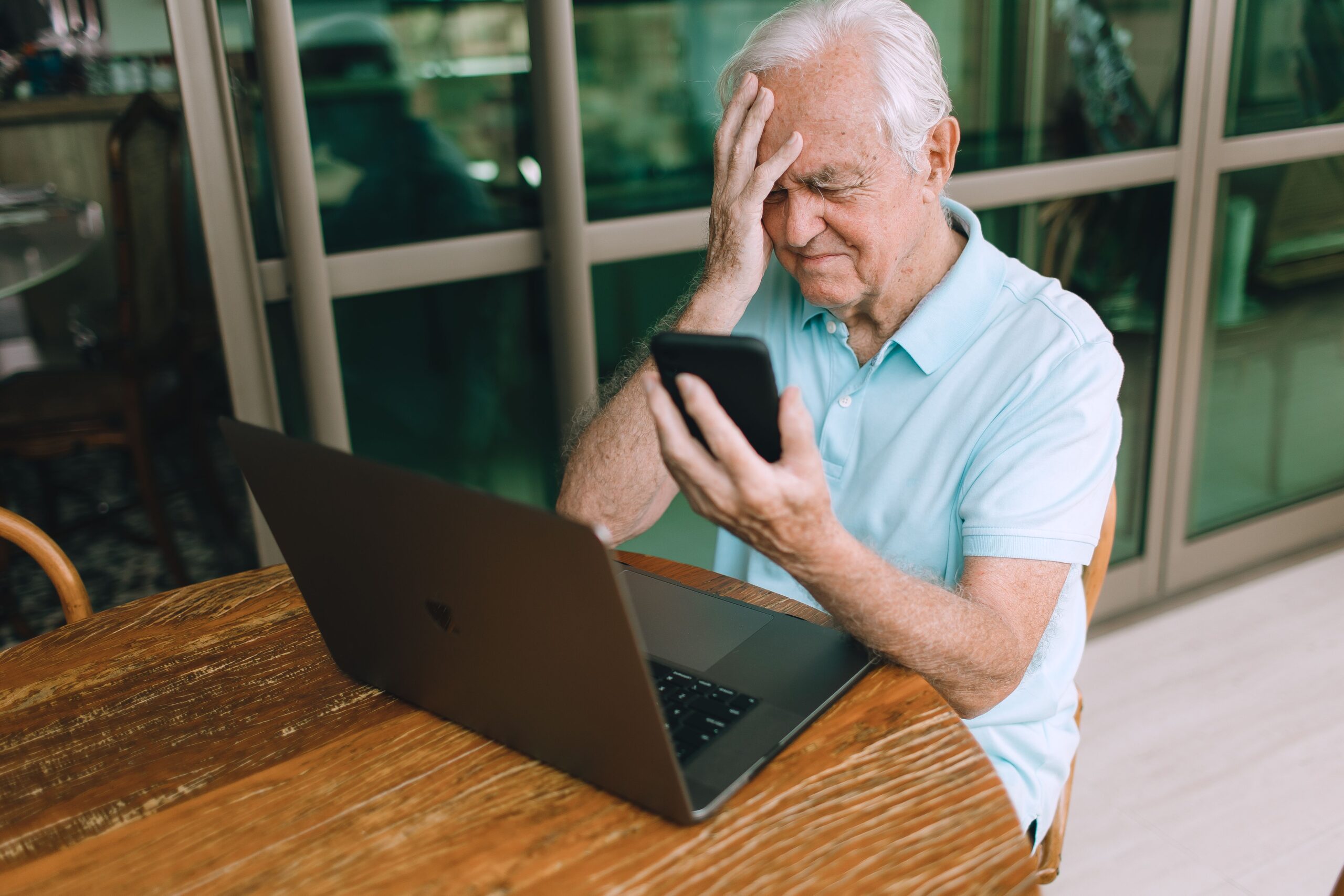 Hombre mayor expresando frustración ante problemas técnicos con su dispositivo móvil