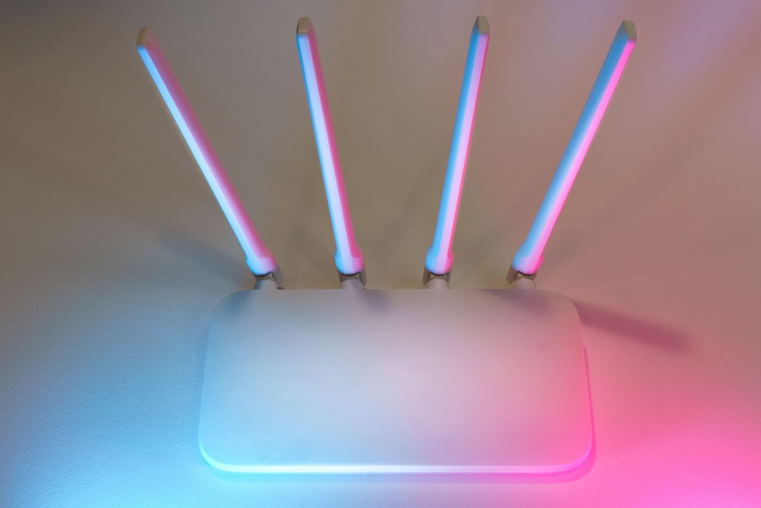 Router inalámbrico moderno de color blanco con antenas y luz ambiental tecnológica.