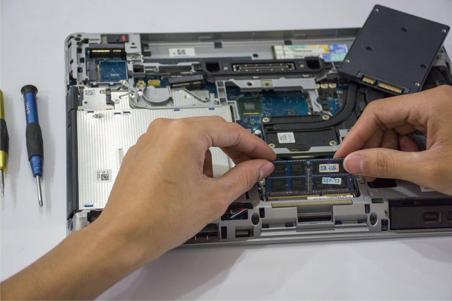Technician assembling internal components of a laptop, representing hardware maintenance and performance improvements.