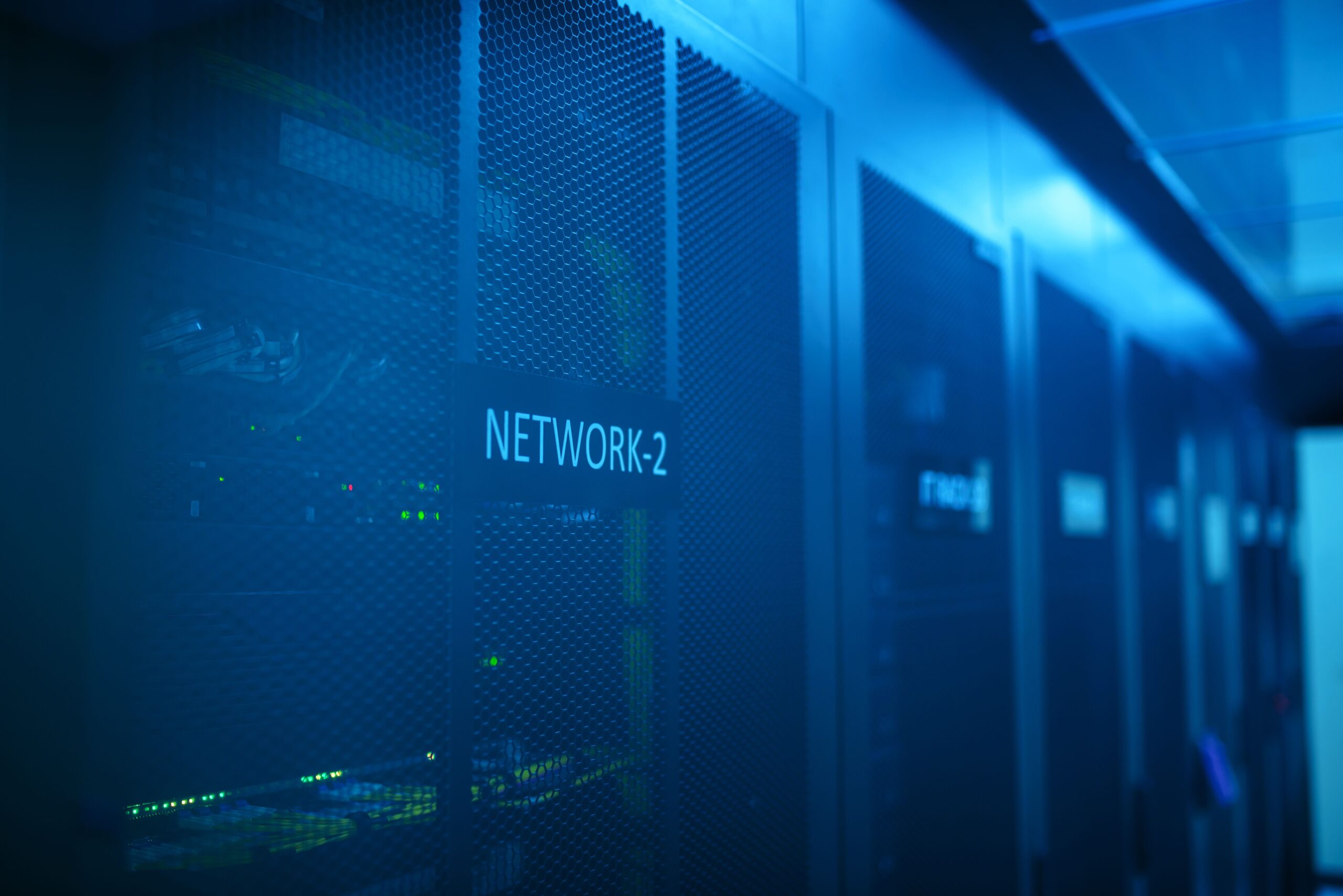 Una sala de servidores profesional con luces azules y racks de red, ilustrando la función del Firewall de Windows en la gestión del tráfico de red.
