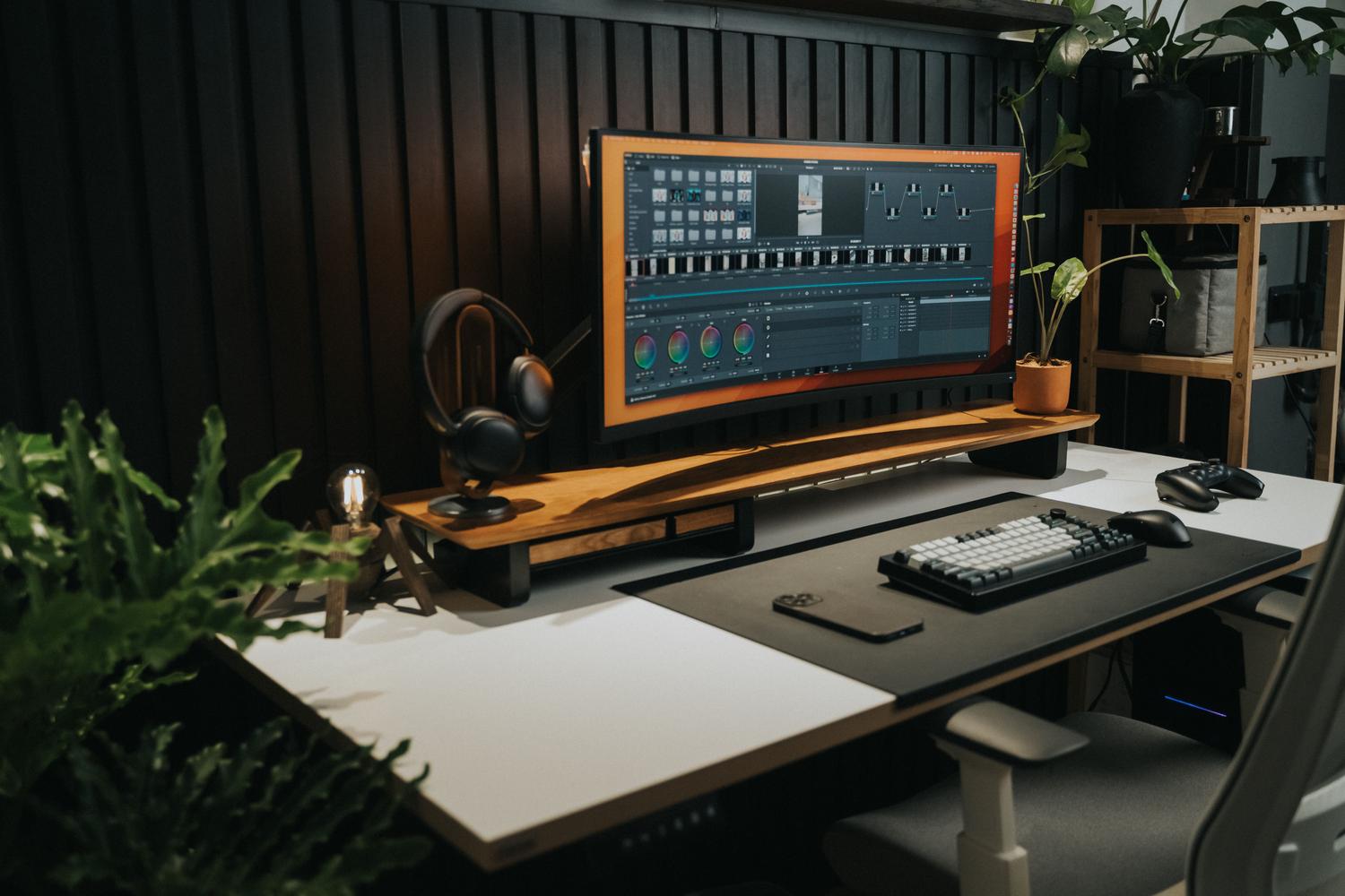 Espacio de trabajo moderno con monitor ultrapanorámico utilizado para edición de vídeo, destacando la gran superficie horizontal.