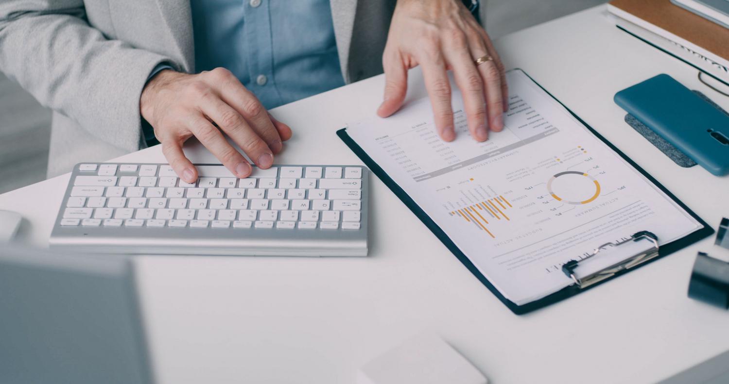 Profesional analizando un informe financiero detallado en su escritorio, ilustrando el uso de hojas de cálculo compatibles.
