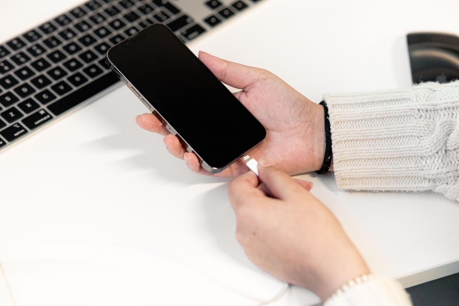 Persona conectando su teléfono móvil al cargador para asegurar que la batería no se agote durante la actualización.