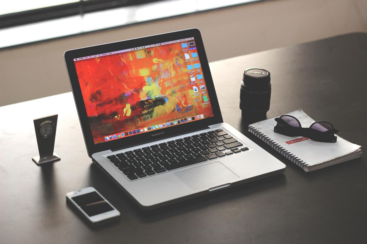 Espacio de trabajo limpio y organizado con un MacBook, ideal para representar la productividad en entornos empresariales.