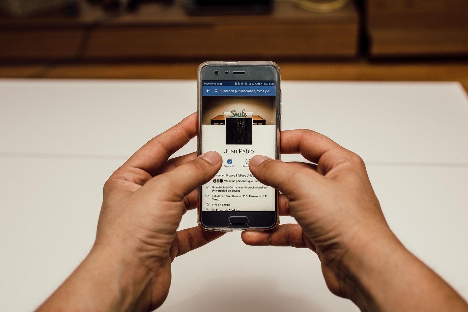 Primer plano de manos manejando un smartphone, ideal para ilustrar la parte técnica de configurar ajustes y privacidad en la aplicación.