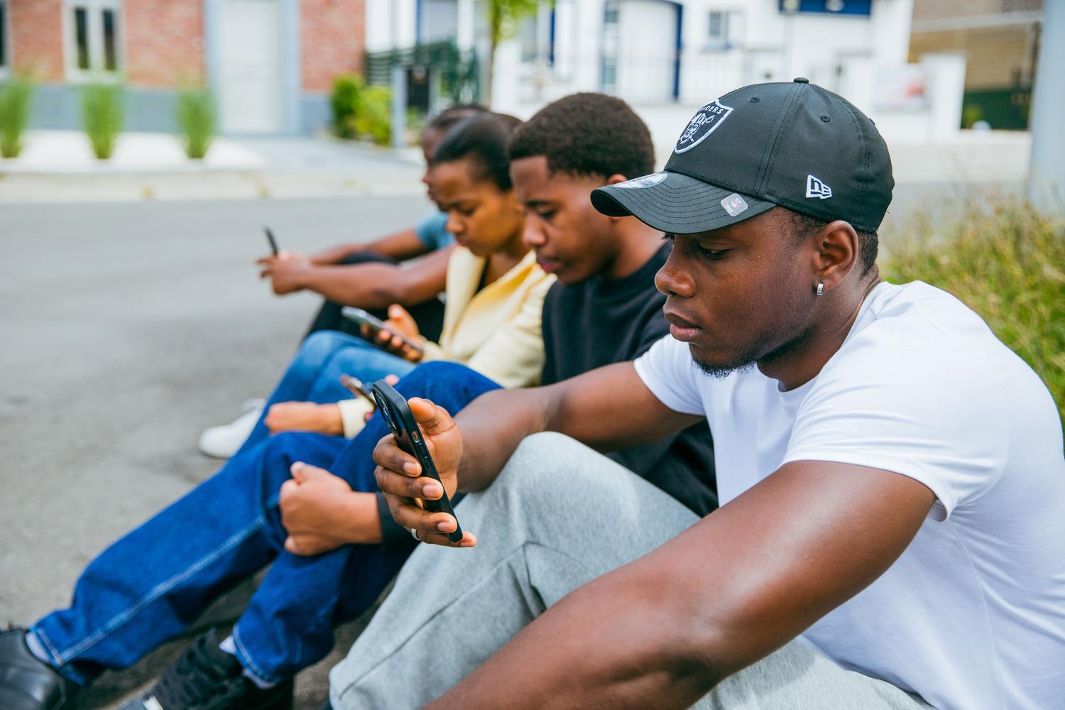 Grupo de jóvenes utilizando sus teléfonos móviles, reflejando el aspecto social, las tendencias y la perspectiva de los creadores de contenido.