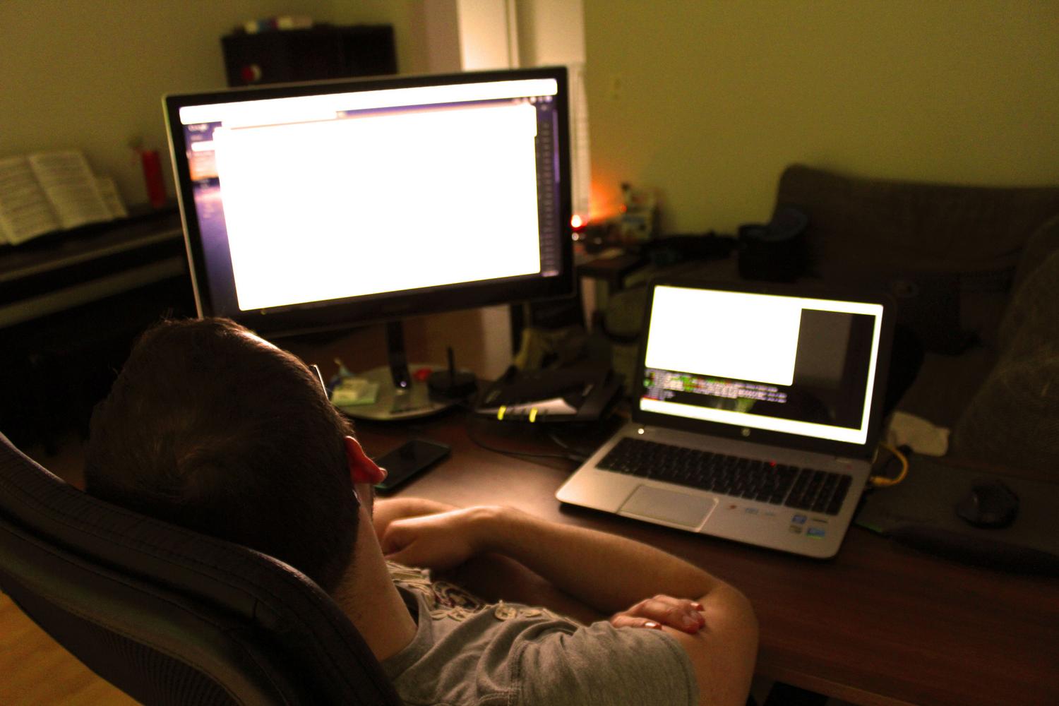 Persona trabajando con un ordenador y monitor externo en casa, representando la fase de configuración técnica del router y el DDNS.