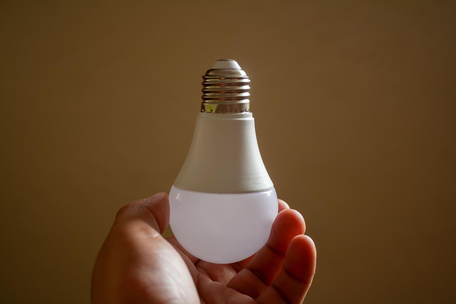 Mano sosteniendo una bombilla LED de bajo consumo, representando la eficiencia energética y la sostenibilidad.