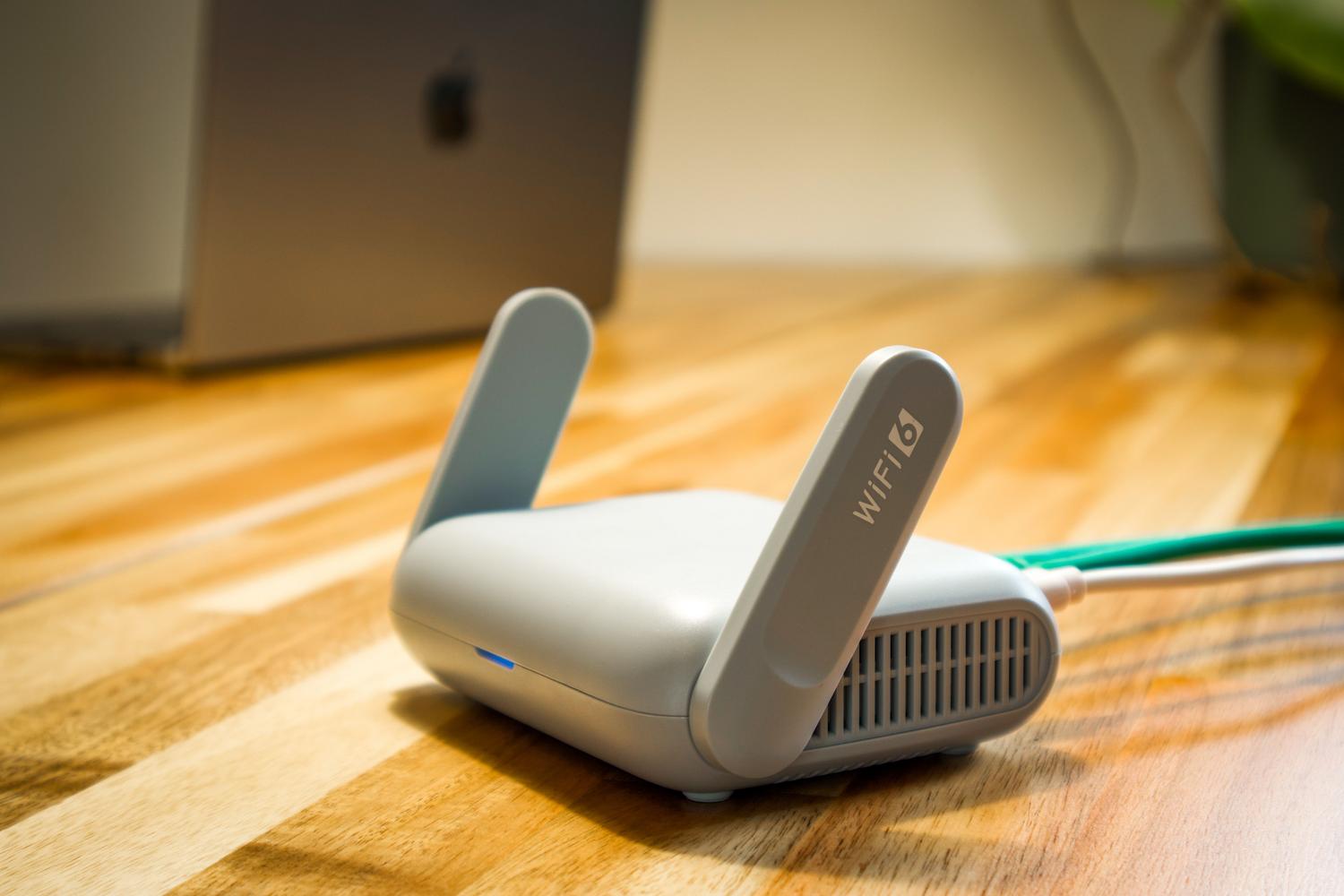 Modern WiFi 6 router on a wooden desk, the central device for configuring QoS network priority.