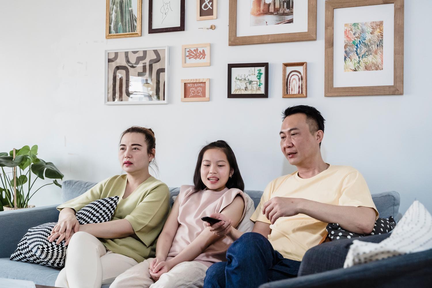 Familia relajada en el sofá viendo la televisión en un ambiente hogareño seguro y acogedor.