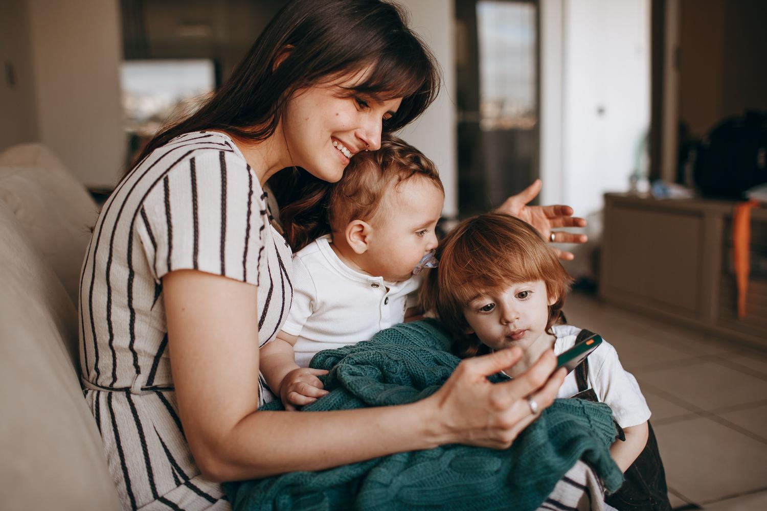 Madre gestionando el uso de la tecnología con sus hijos pequeños en casa.