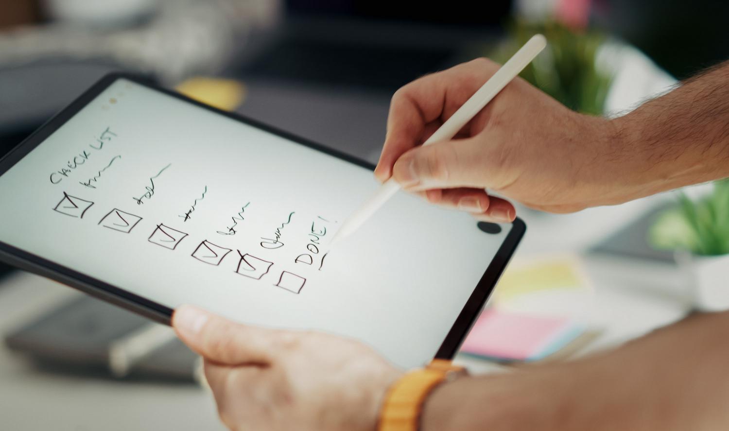 Primer plano de una mano utilizando una lista de verificación digital en una tablet, ilustrando el uso de plantillas avanzadas y SOPs.