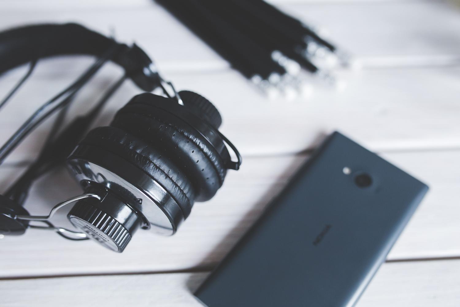 Smartphone y auriculares sobre una mesa, ideal para la sección de optimización de audio y vídeo en dispositivos móviles.