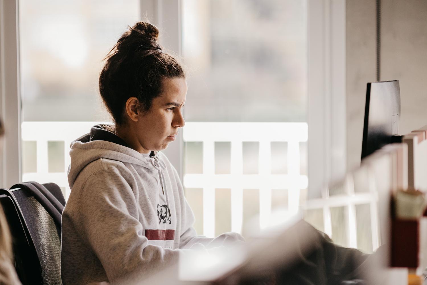 Vista lateral de una mujer trabajando intensamente en un ordenador, ejemplificando la productividad al configurar perfiles de trabajo personalizados.