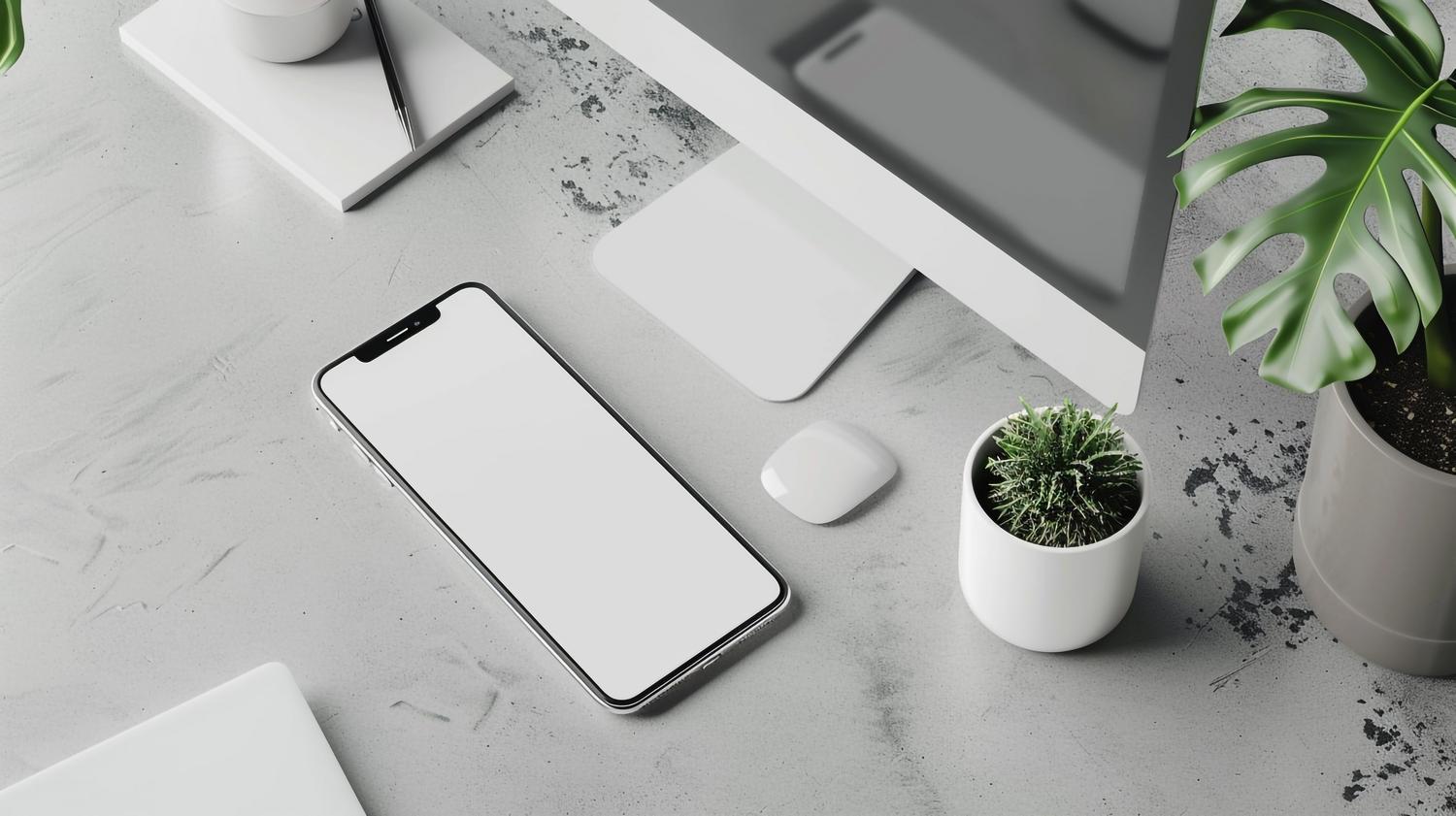 Espacio de trabajo minimalista y limpio con un smartphone, ordenador y plantas, simbolizando la organización de la vida digital.