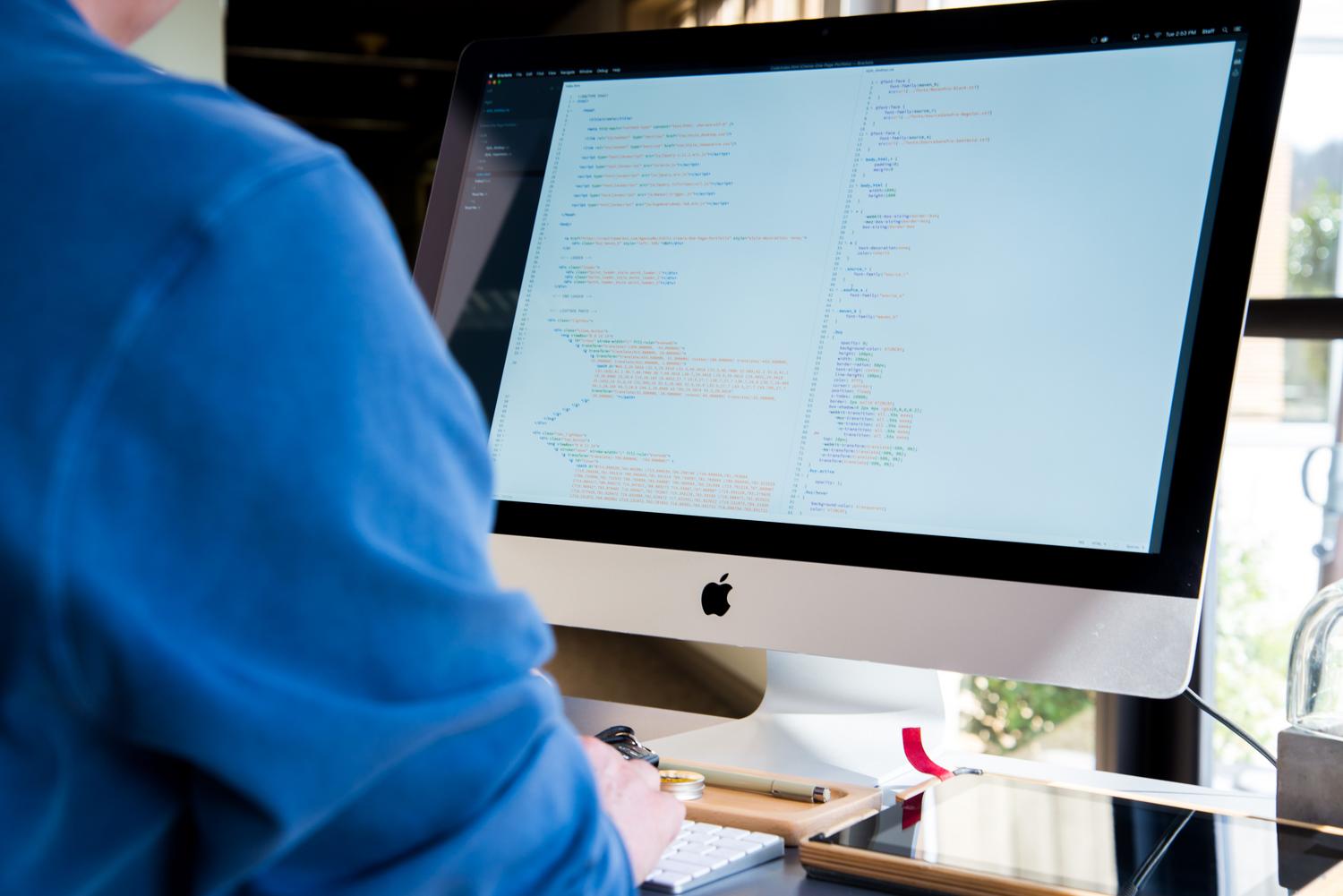 Programador trabajando en un ordenador en una oficina moderna, representando la figura del desarrollador de software.