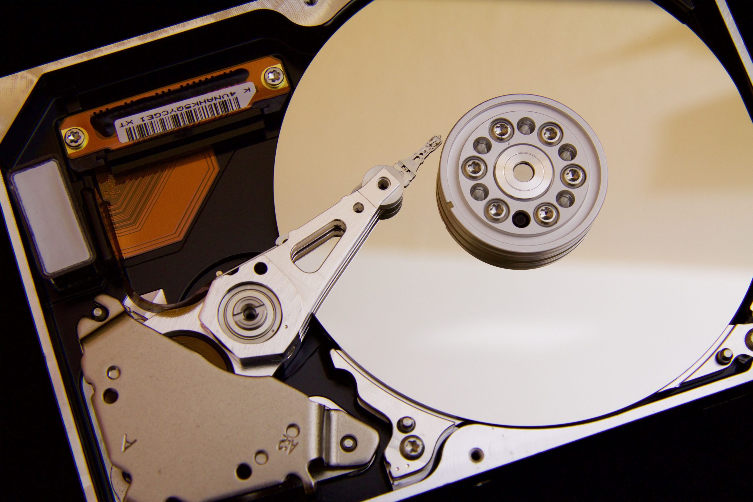 Detalle interno de un disco duro mostrando el brazo actuador y los platos magnéticos, perfecto para explicar el funcionamiento de SMART y los fallos físicos.