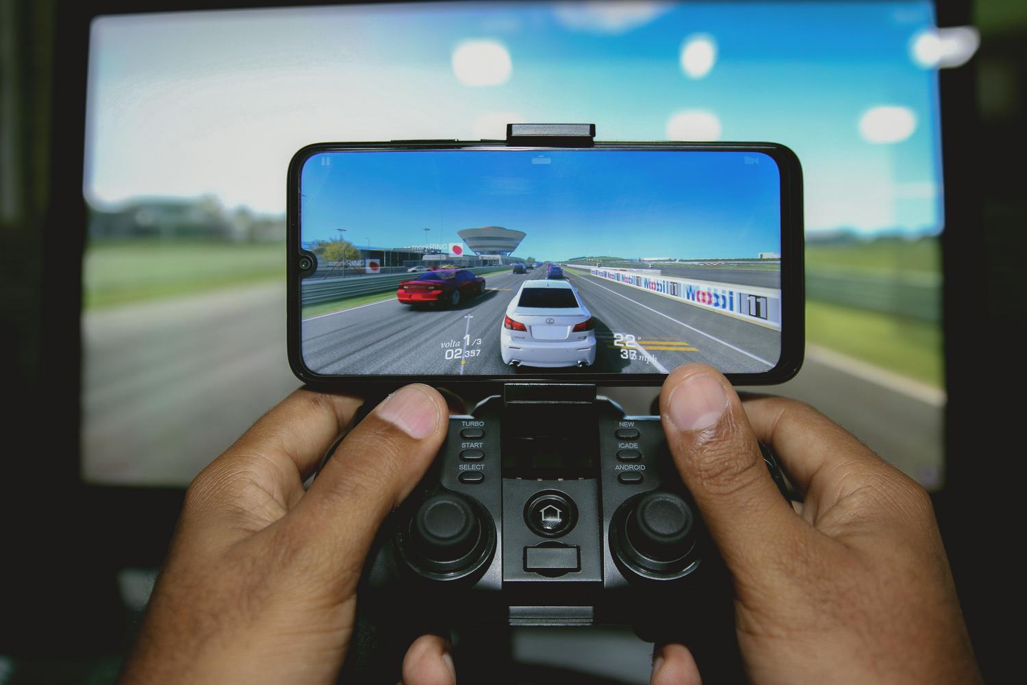 Smartphone integrado en un mando de juegos ejecutando una carrera, ilustrando el uso del móvil como controlador.
