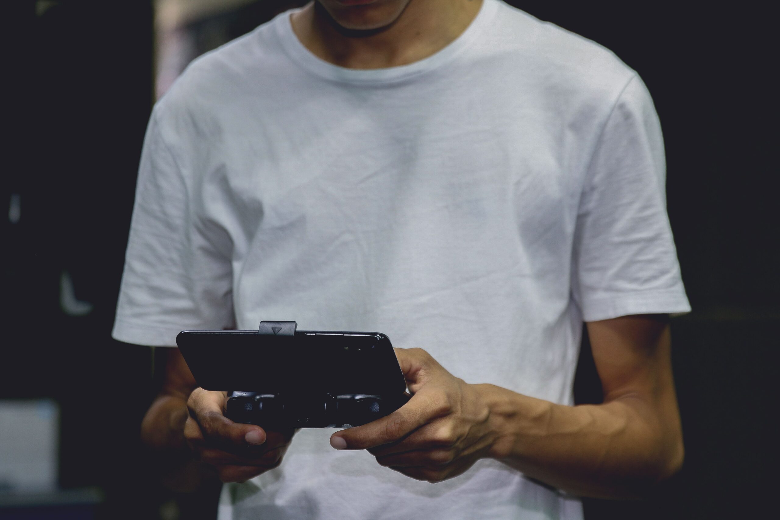 Joven utilizando un mando gaming acoplado a su teléfono móvil en interiores.