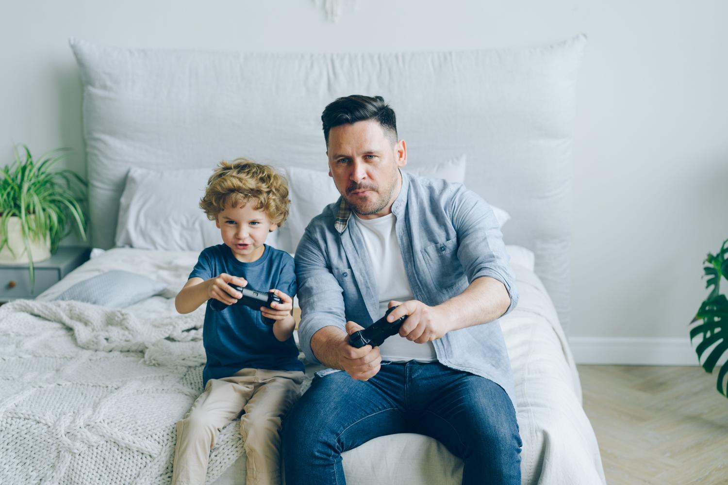 Padre e hijo jugando videojuegos juntos, ejemplificando la creación de múltiples perfiles de usuario en un mismo sistema.