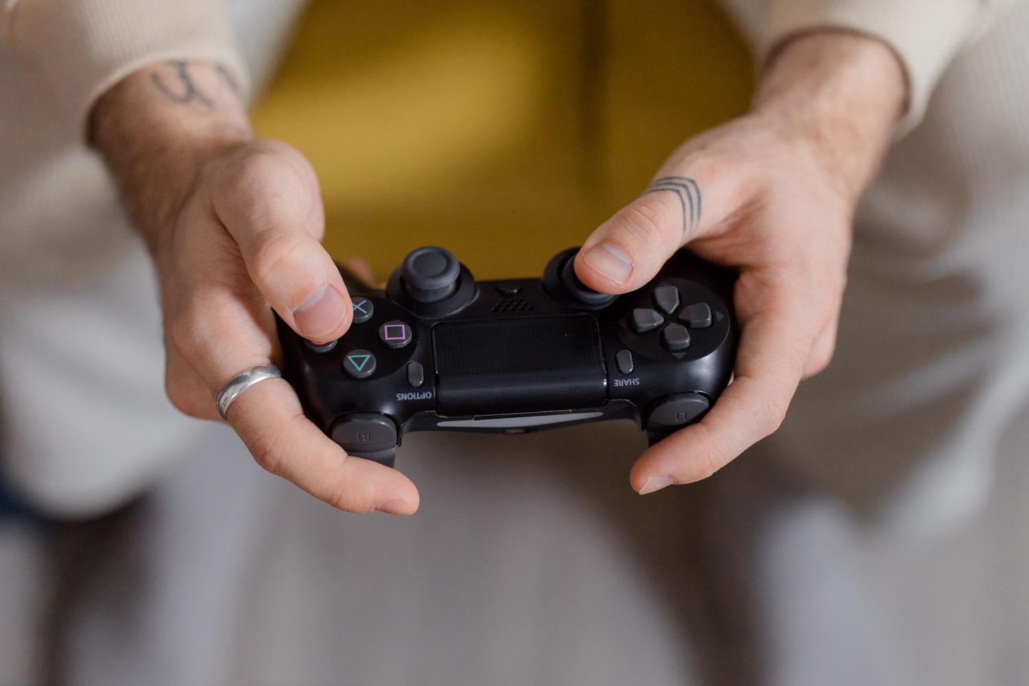 Persona sosteniendo un mando de videojuegos negro, representando la personalización de perfiles de usuario.