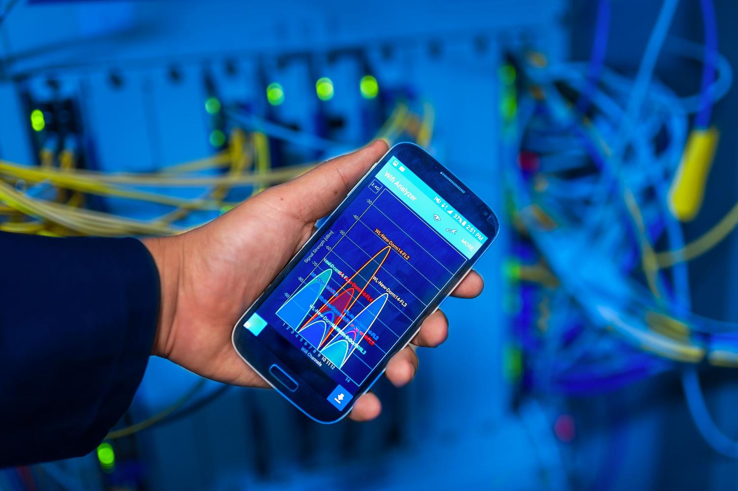 Persona sosteniendo un smartphone en un entorno de servidores, ilustrando la conexión entre el móvil y el NAS.