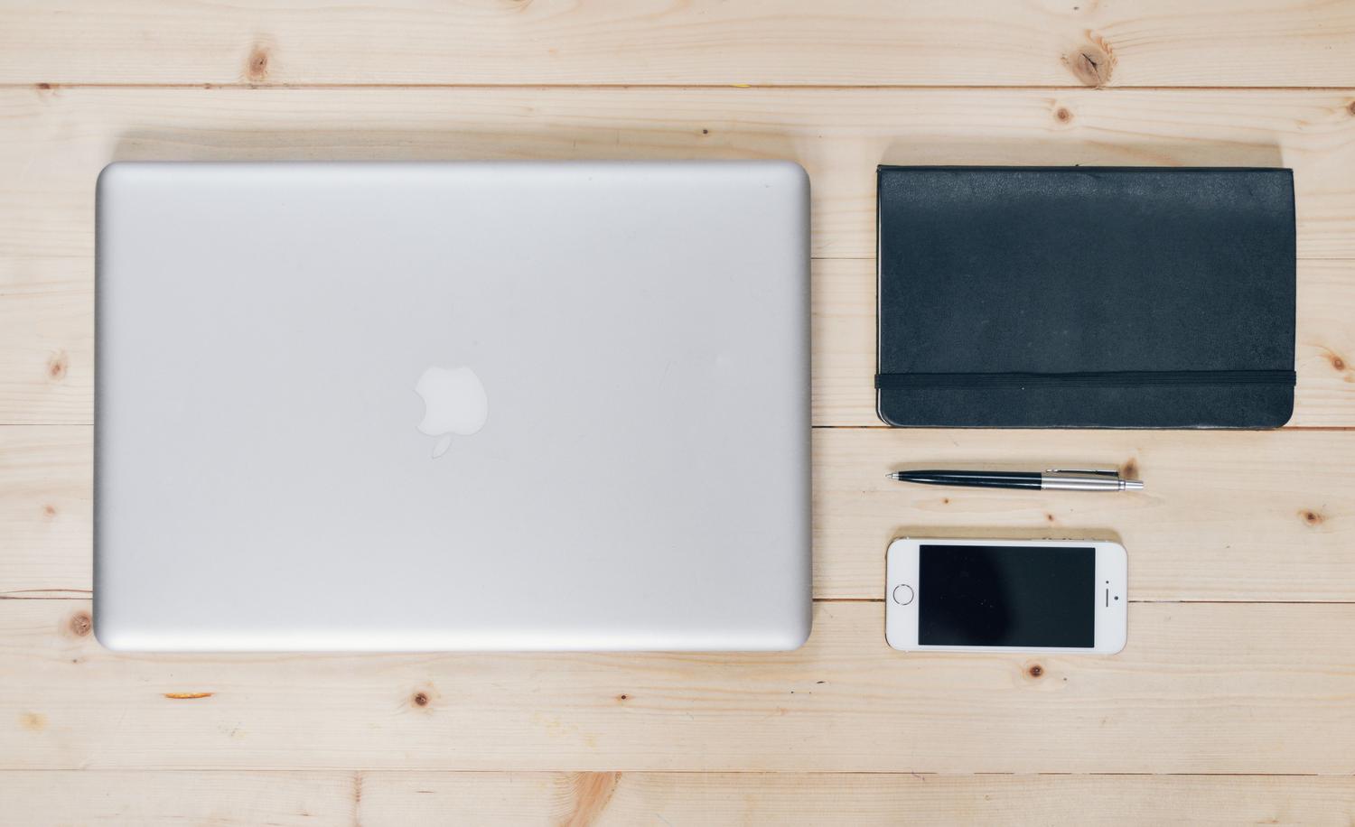 Escritorio organizado con gadgets tecnológicos y cuaderno, representando un enfoque sistemático y eficiente de la productividad digital.
