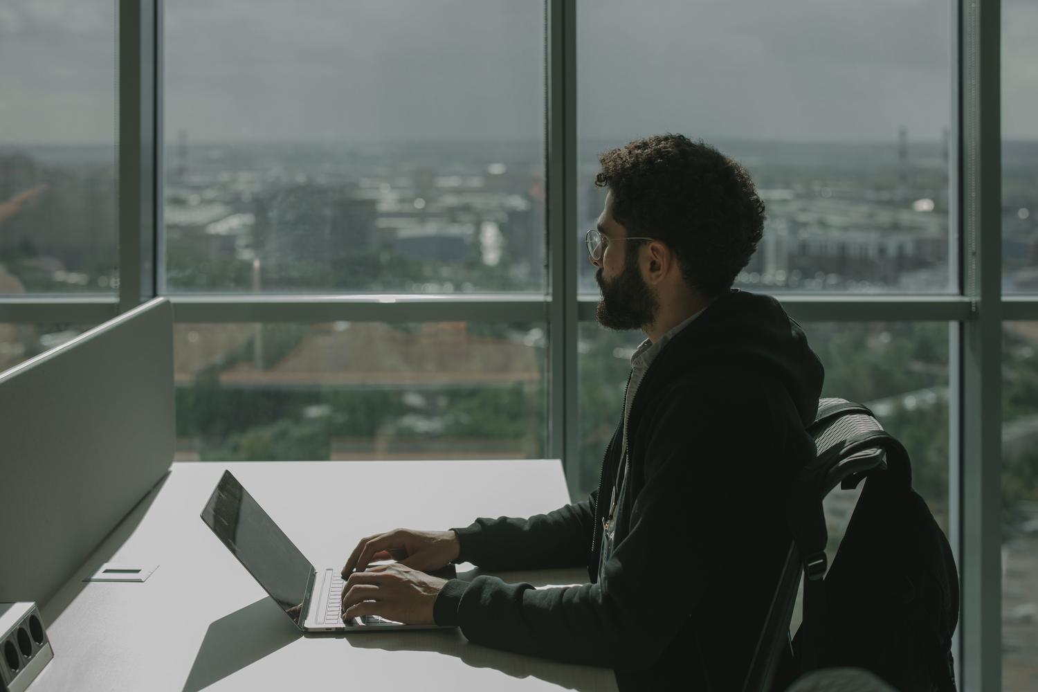 Hombre profesional trabajando concentrado en un portátil en una oficina moderna, representando la creación de documentación y guías visuales.