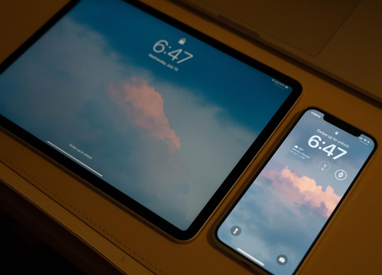 iPhone e iPad con pantallas de bloqueo y fondos de pantalla coordinados, perfecto para ejemplificar la vinculación de fondos con modos de enfoque en iOS.