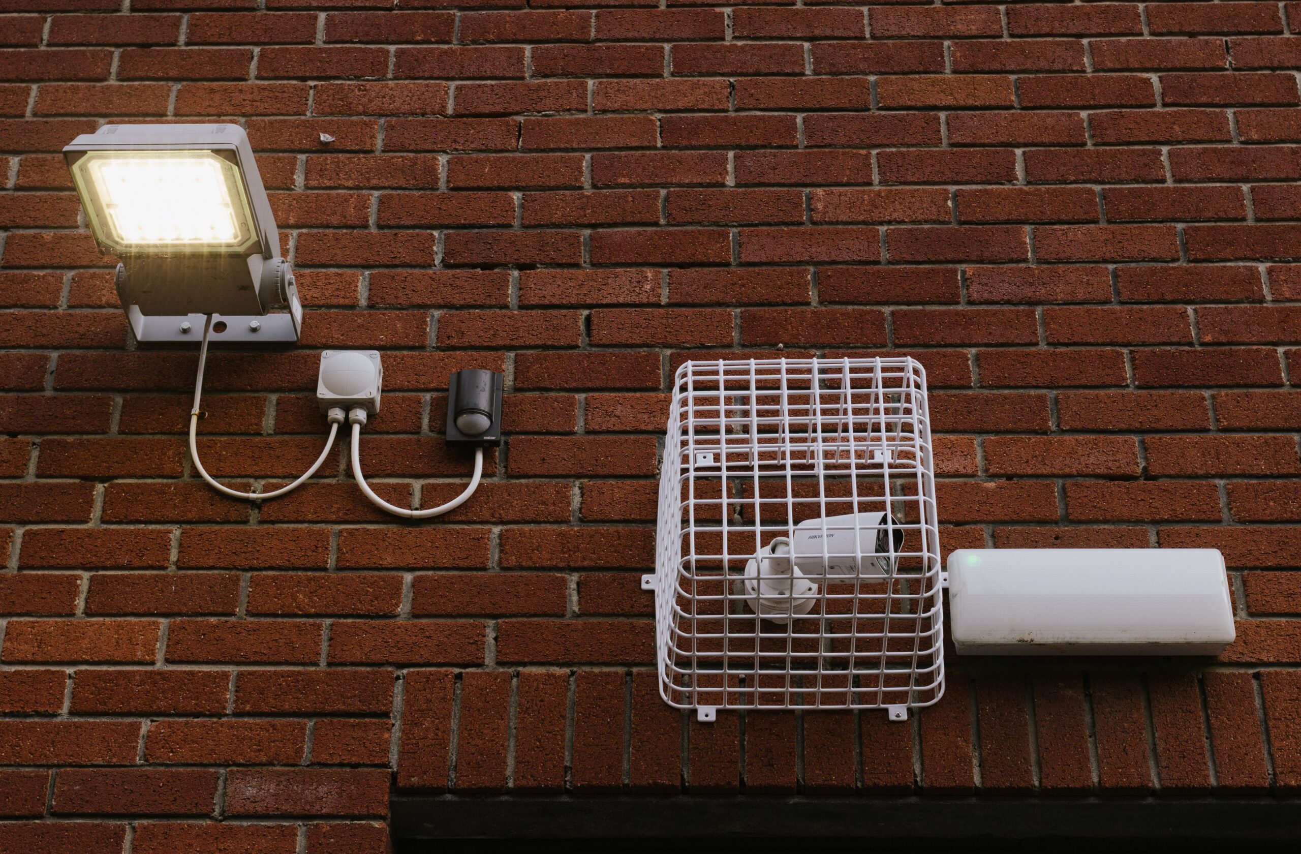 Cámara de seguridad y sensor de movimiento instalados en el exterior de un edificio, expuestos a la intemperie (Clase Ambiental IV).
