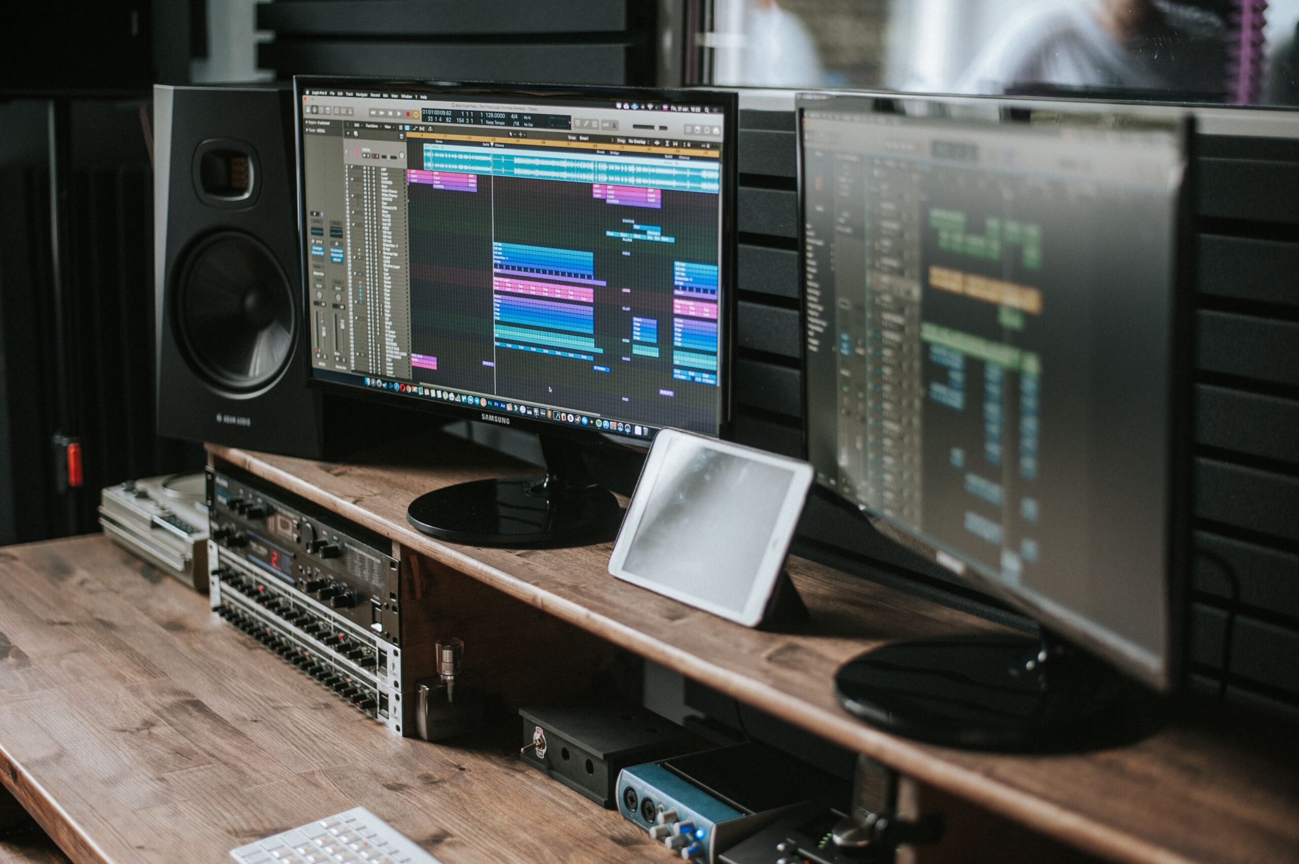 Software de producción musical (DAW) Logic Pro X en monitores duales mostrando la edición de pistas de audio.