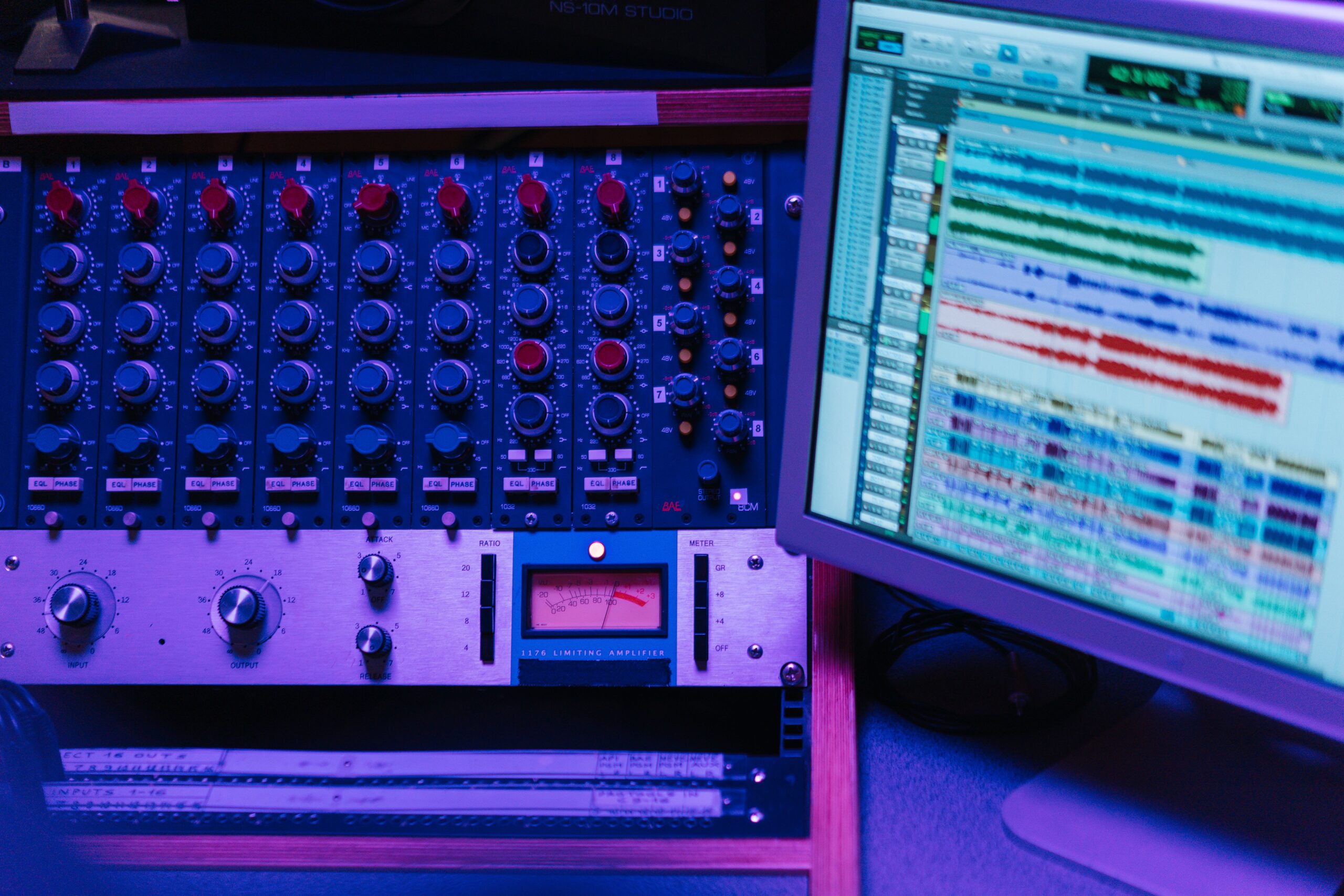 Primer plano de una consola de mezcla analógica y procesadores de señal de audio en un estudio profesional.