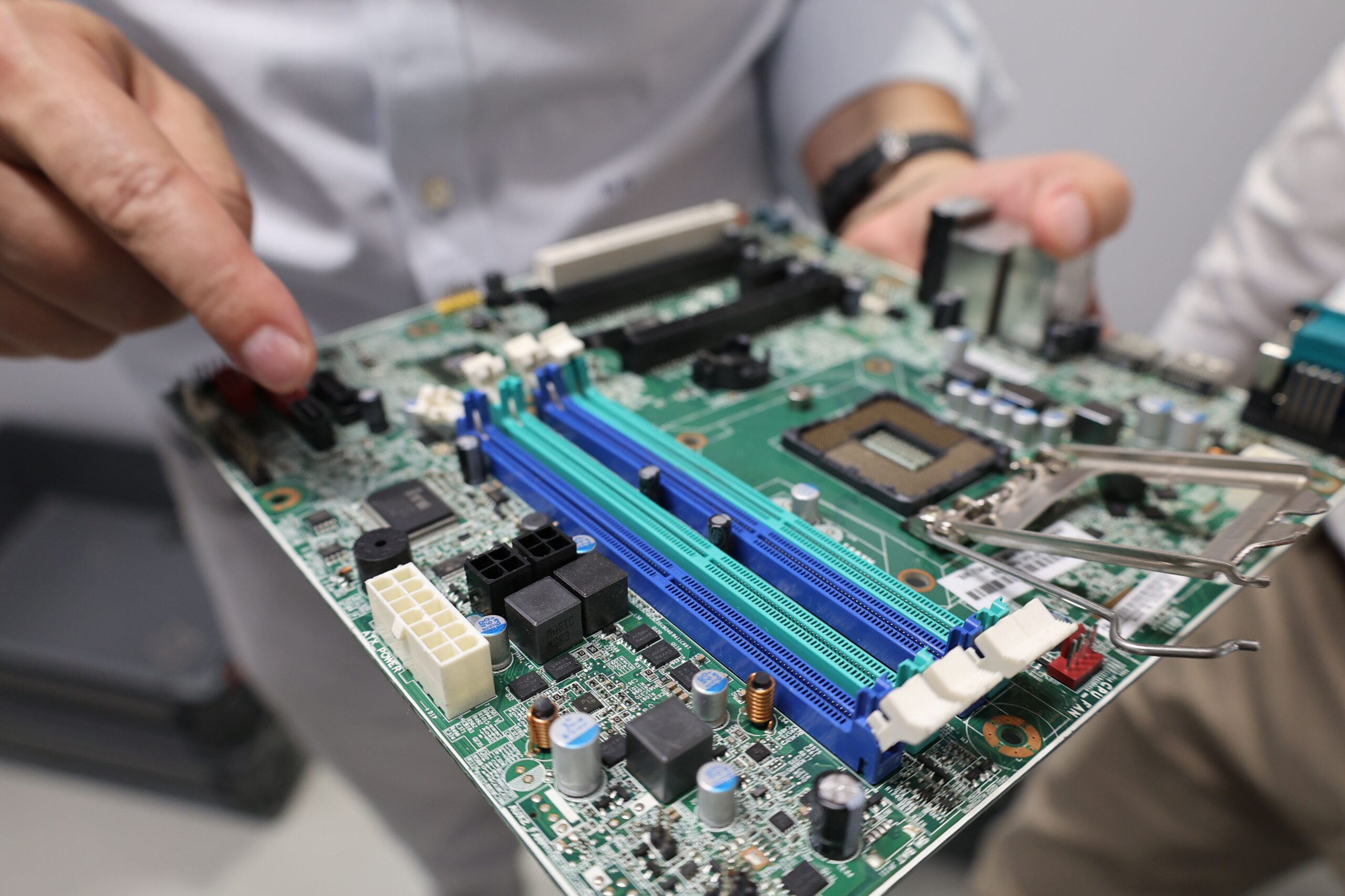 Técnico especializado manipulando una placa base para realizar mantenimiento o actualizaciones de hardware.