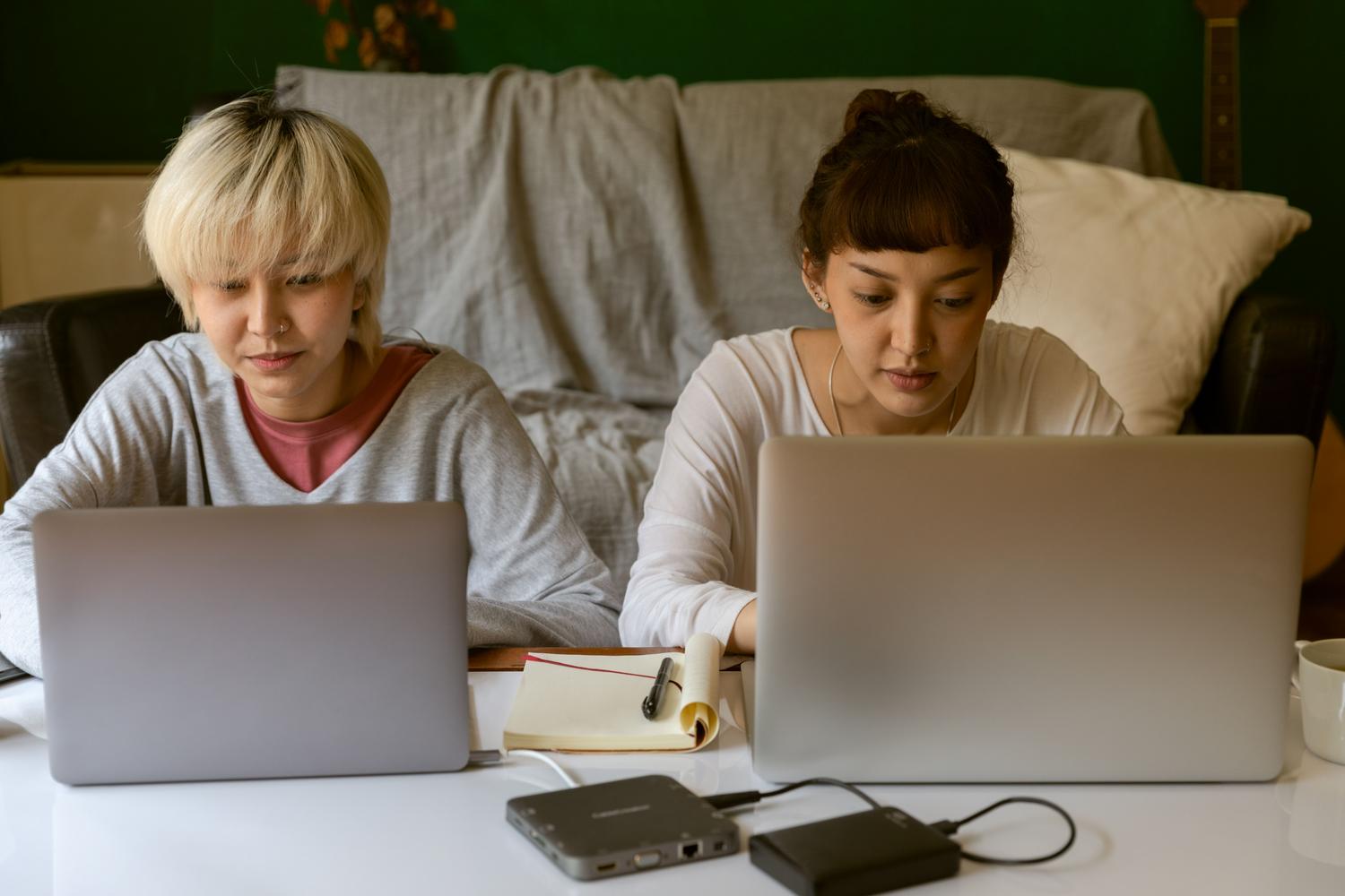 Estudiantes universitarios colaborando con portátiles en un entorno doméstico, ilustrando la integración de OnlyOffice en plataformas educativas.