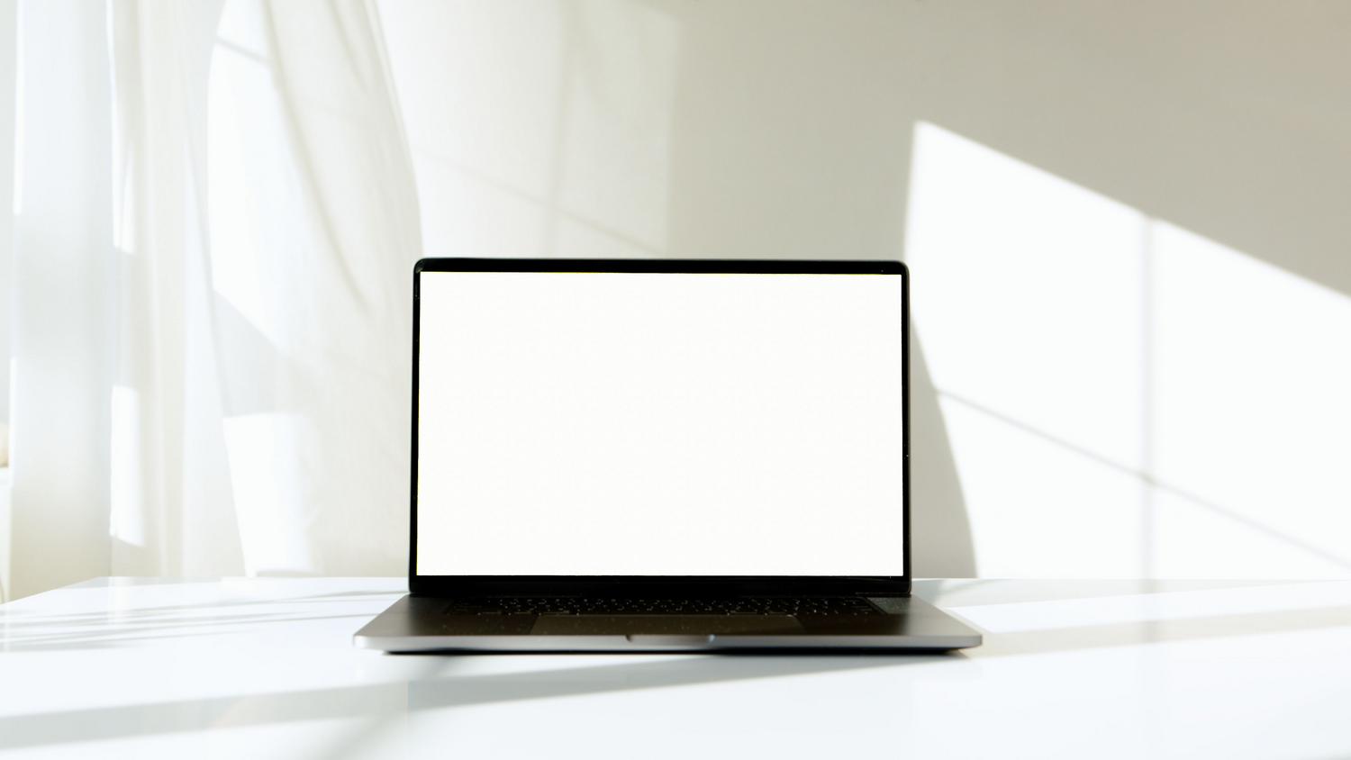 Portátil con pantalla en blanco en un entorno luminoso, simbolizando la rapidez de apertura de archivos con un lector ligero.