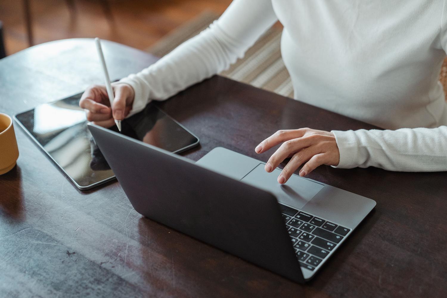 Mujer profesional firmando un documento digital con un lápiz óptico y un ordenador portátil, eliminando la necesidad de imprimir.